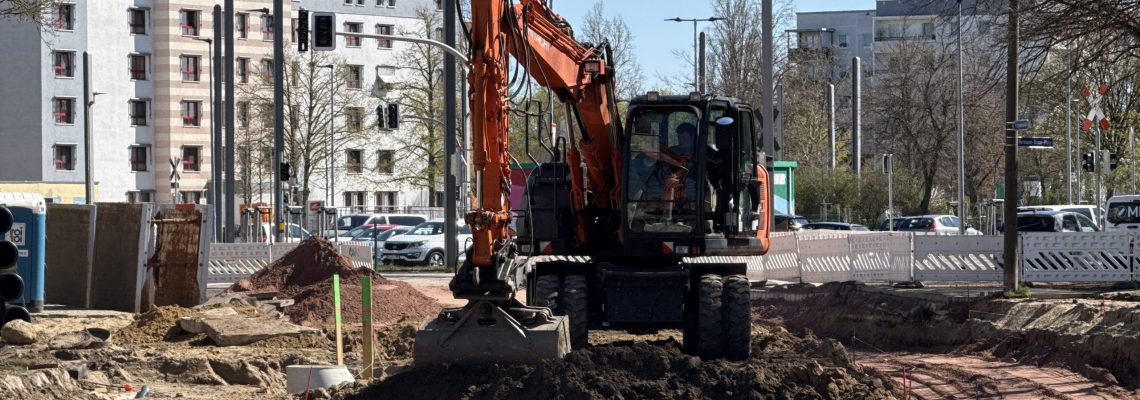 Ein Bagger steht in der Nähe des Hermann-Bruse-Platzes auf einem Erdhügel.